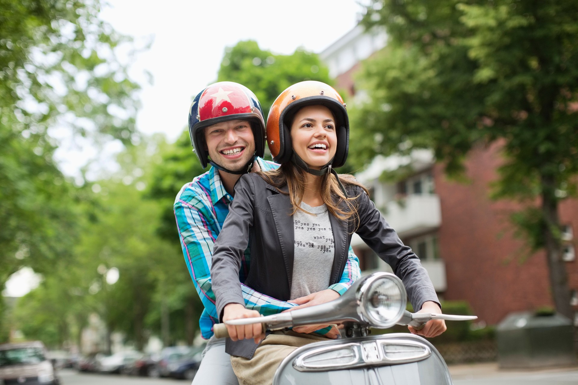 Couple riding scooter together on city street