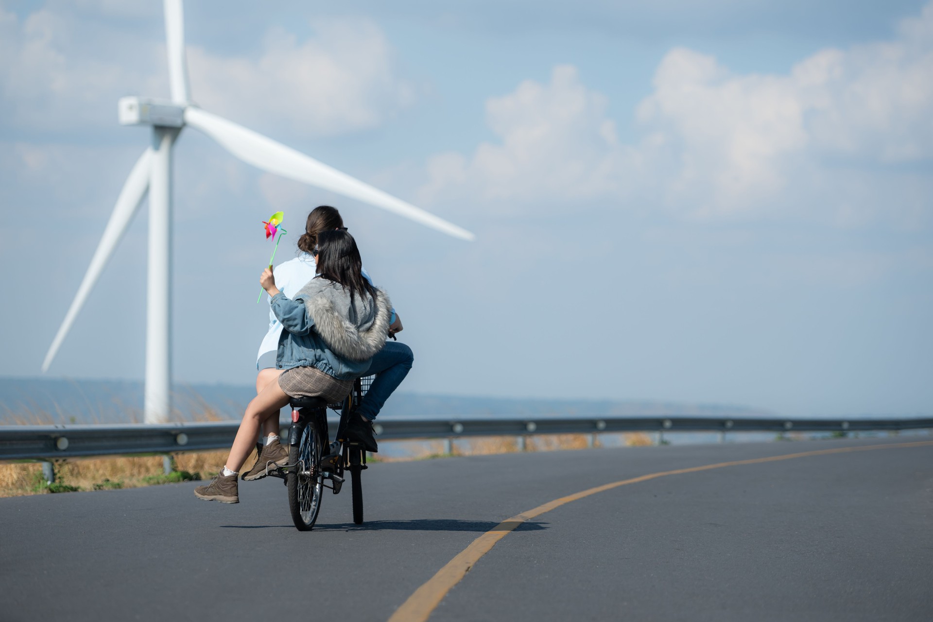 Back view of a young woman riding a bicycle with her boyfriend on the road