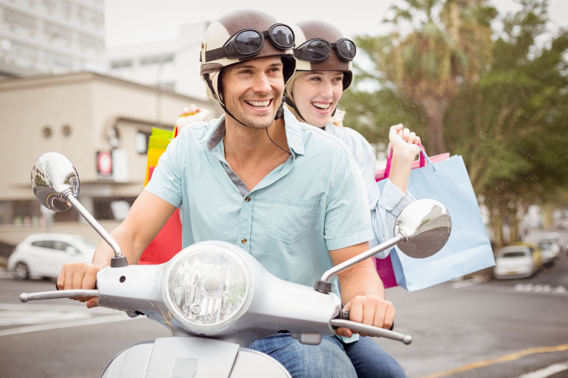 Hip young couple riding scooter with shopping bags